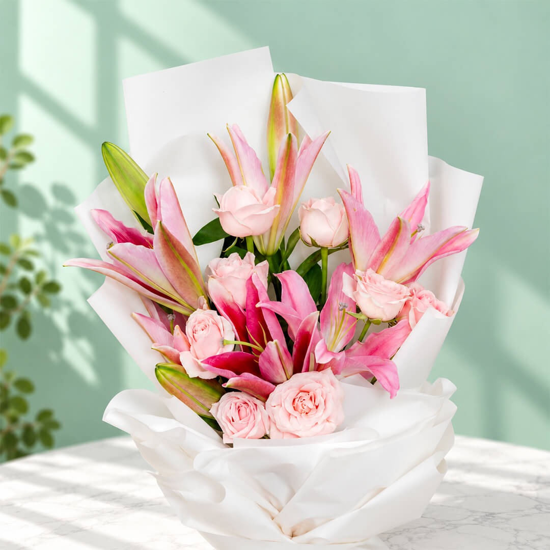 Bouquet of 12 pink lily and rose stems wrapped in non-woven paper.