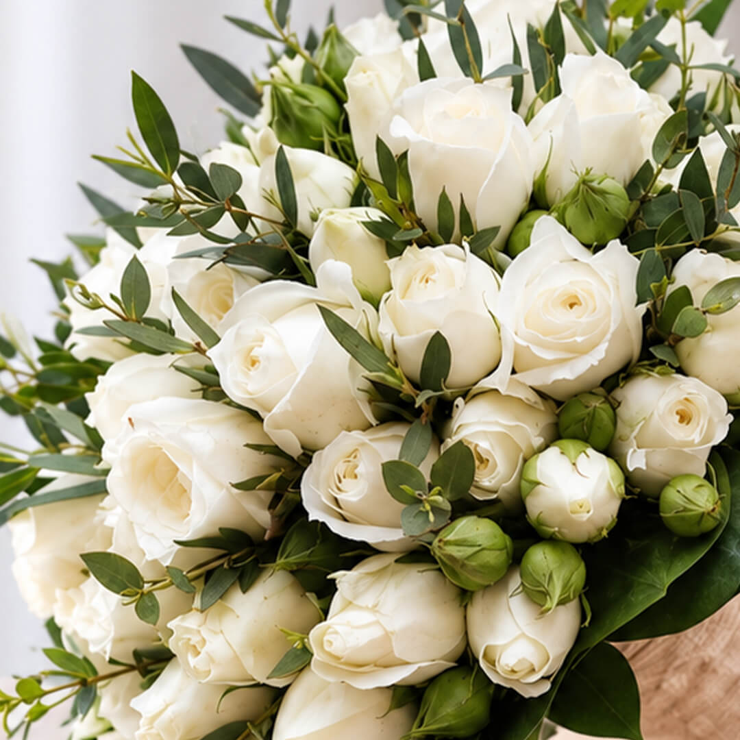 Classic white rose wedding bouquet with fresh green leaves and a simple hand-tied finish for sophisticated bridal styling.
