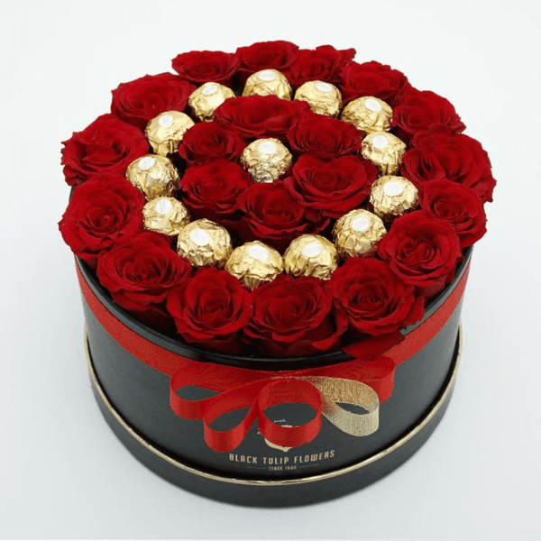Red roses arranged with 16 Ferrero Rocher chocolates in a black round gift box