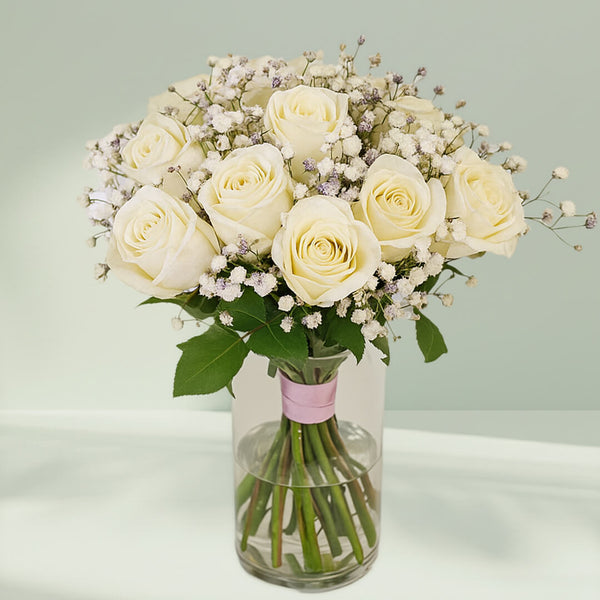 20 white roses with gypsophila arranged in a cylindrical glass vase.