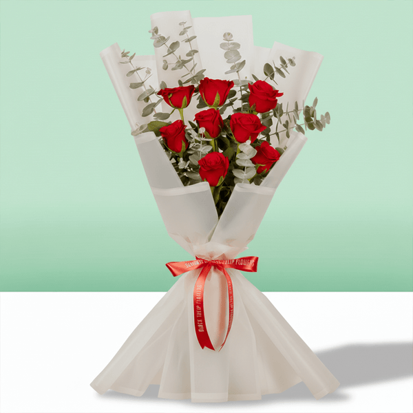 Bouquet of 8 pink roses with eucalyptus wrapped in non-woven paper.