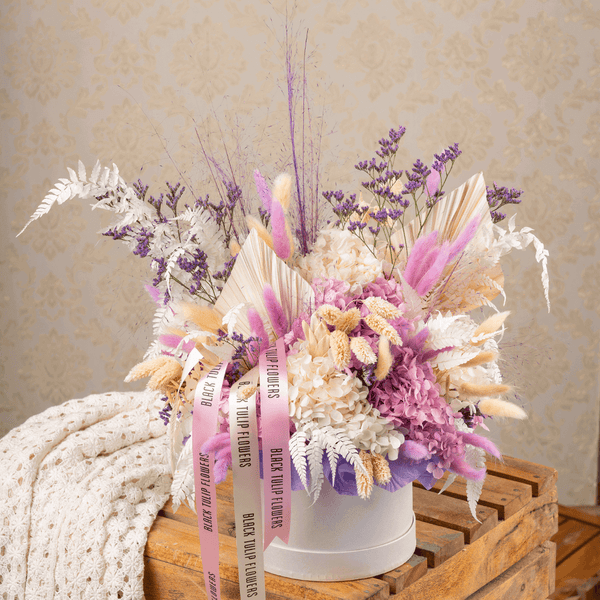 Arrangement featuring assorted dried and preserved flowers in white round box.