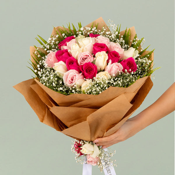 Deep pink, blush and white roses with baby’s breath wrapped in layered brown non-woven paper