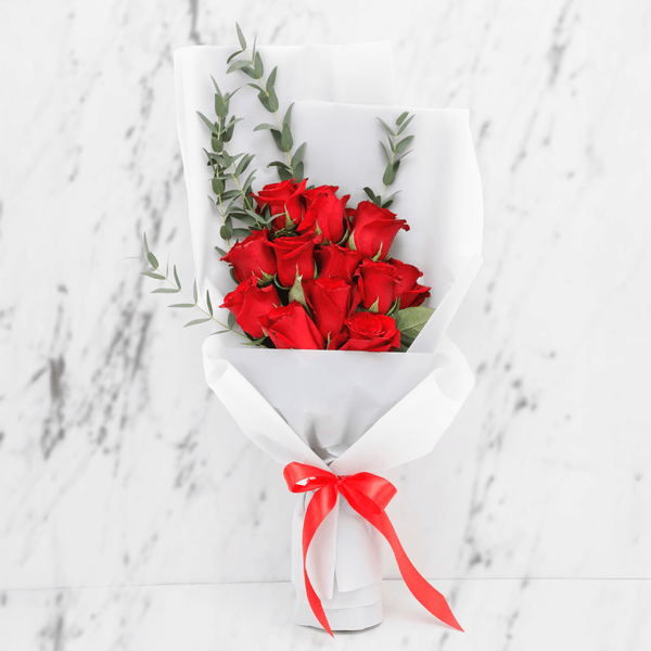 Fresh red roses bouquet with added greenery in a white wrap finished with a red ribbon.