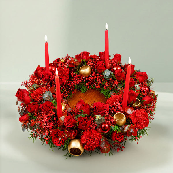A fresh festive flower wreath with roses, carnations, eucalyptus, gypsophila, fresh greenery, and an LED taper candle.