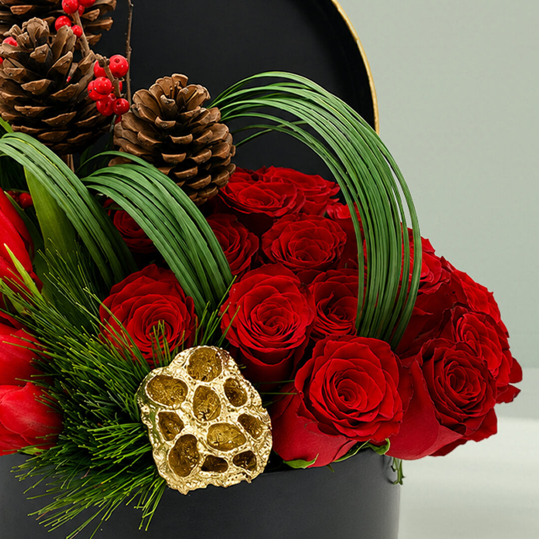 Christmas festive flower box featuring red roses, exotic blooms, pinecones, foliage, and seasonal accents