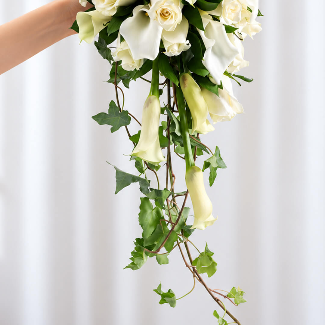 Elegant white Calla lily and rose bridal bouquet with lush greenery and minimalist wrap
