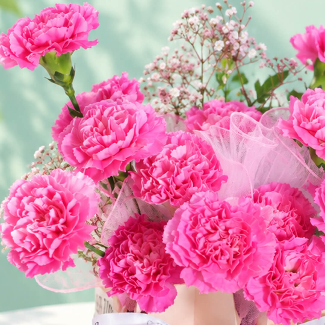 Pink carnations and gypsophila arranged in a decorative flower bag