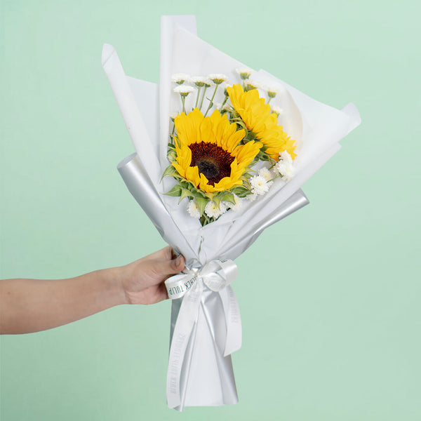 Fresh sunflower bouquet wrap with white wrapping and ribbon for cheerful gifting.
