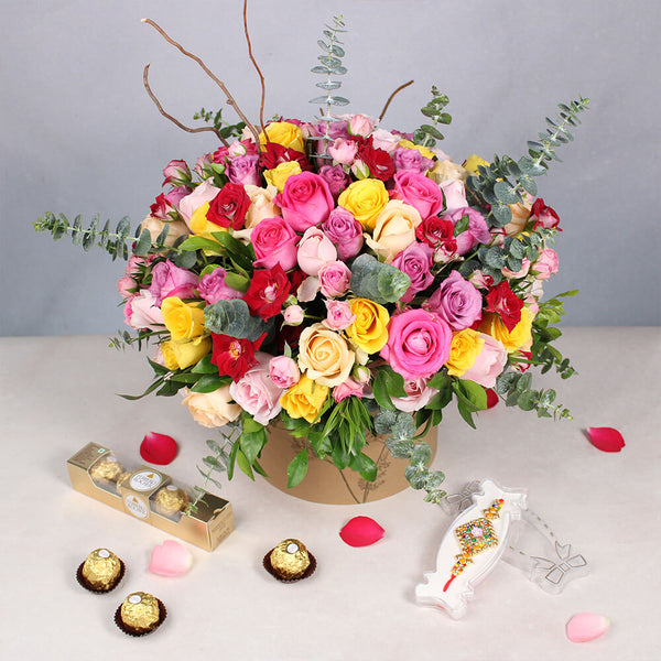 Assorted Roses and Spray Roses in a round flower box with Gemstone Rakhi and Ferrero Rocher chocolates.
