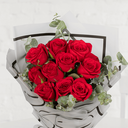 Red roses with eucalyptus greenery wrapped in layered grey paper