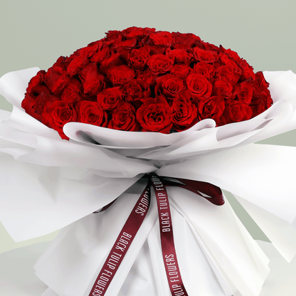 Romantic hand-tied red roses bouquet in white wrapping with burgundy ribbon