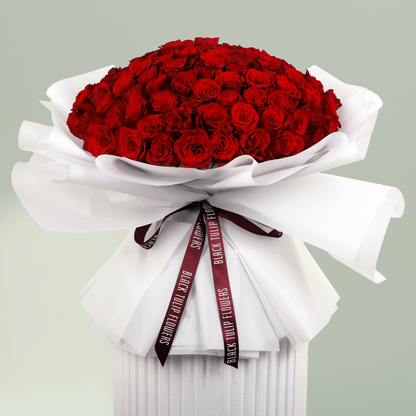 Romantic hand-tied red roses bouquet in white wrapping with burgundy ribbon