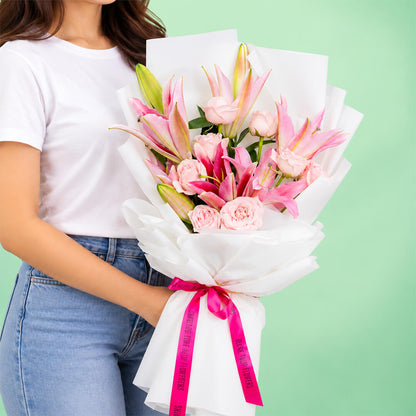 Bouquet of 12 pink lily and rose stems wrapped in non-woven paper.