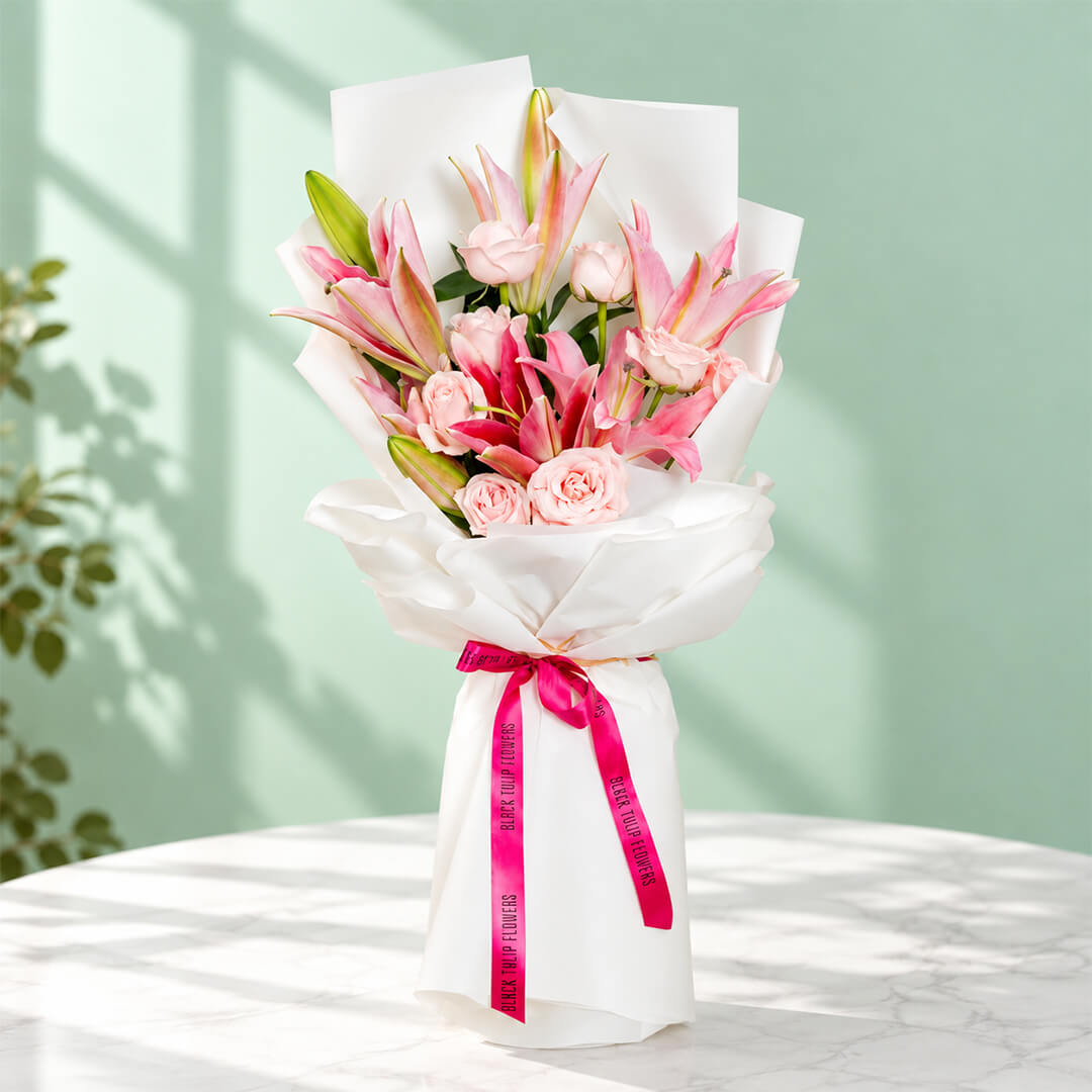 Bouquet of 12 pink lily and rose stems wrapped in non-woven paper.