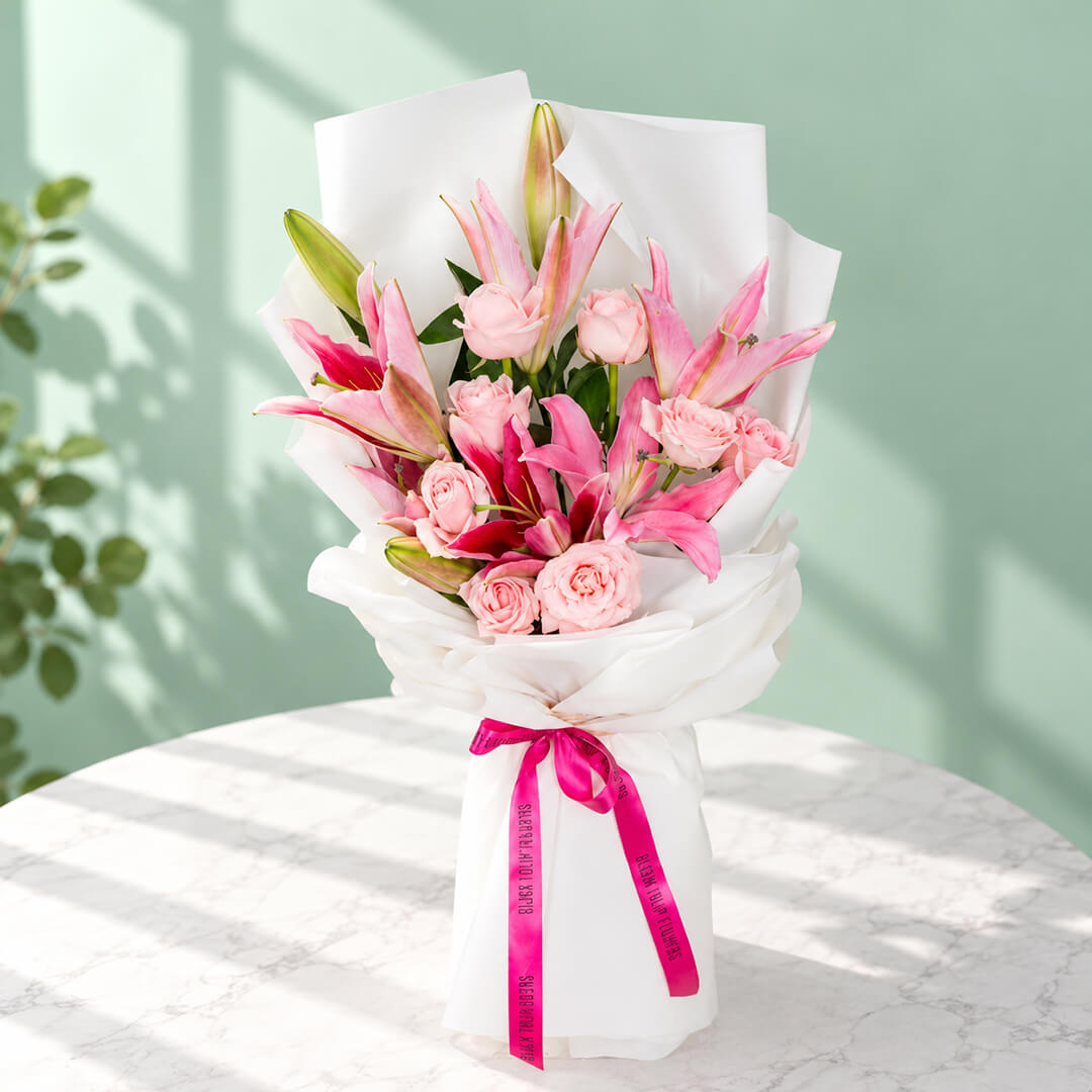 Bouquet of 12 pink lily and rose stems wrapped in non-woven paper.