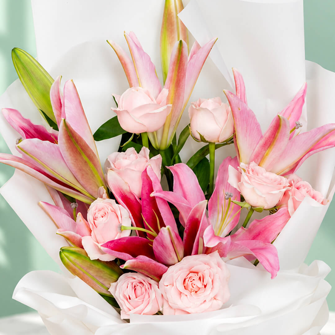 Bouquet of 12 pink lily and rose stems wrapped in non-woven paper.