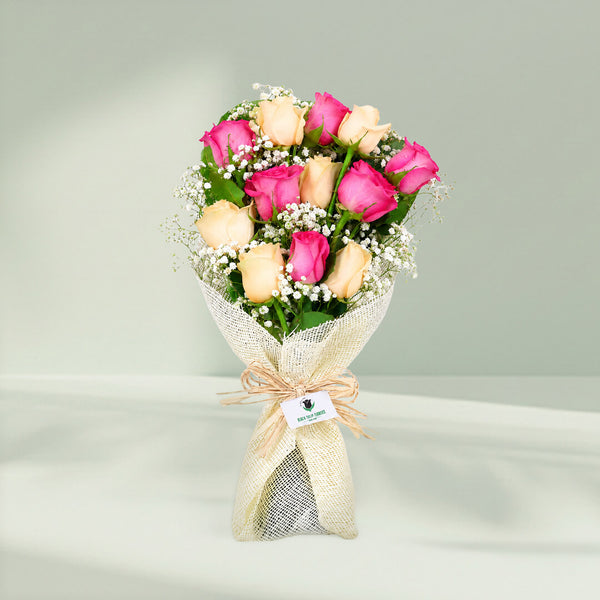 12 stem pink and peach rose bouquet with fillers wrapped in non-woven paper