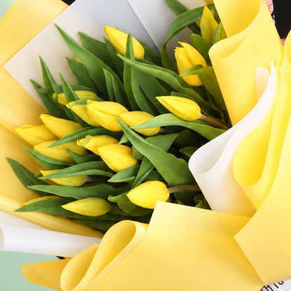 20 fresh yellow tulips arranged in a bouquet with non-woven paper wrapping