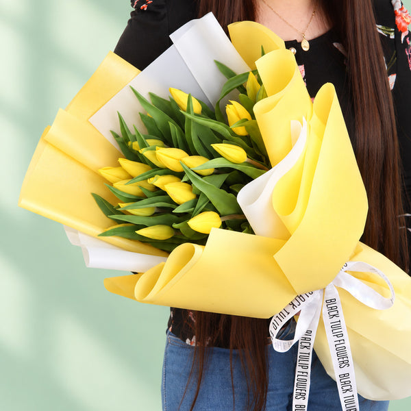 20 fresh yellow tulips arranged in a bouquet with non-woven paper wrapping