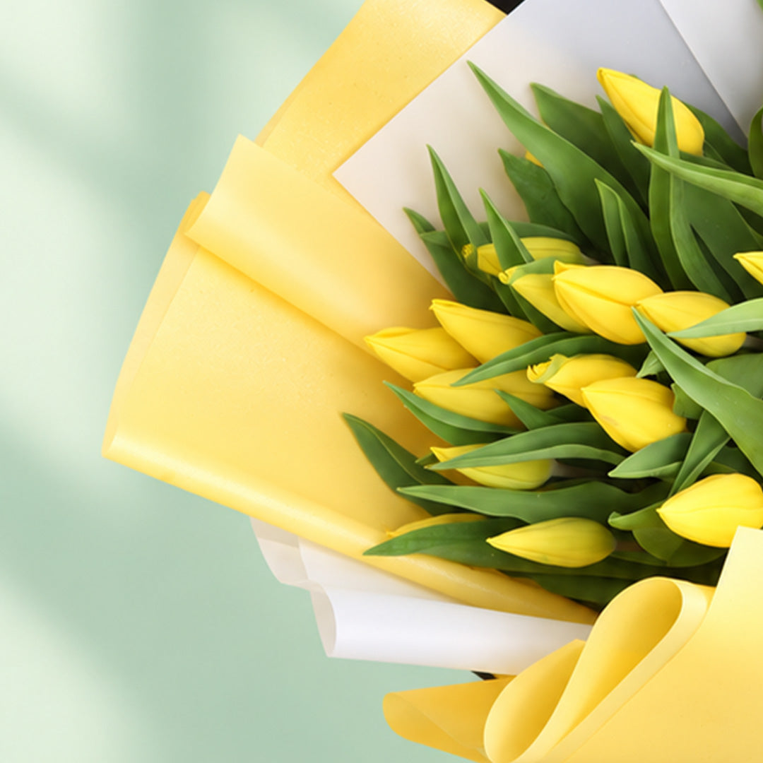 20 fresh yellow tulips arranged in a bouquet with non-woven paper wrapping