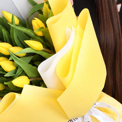 20 fresh yellow tulips arranged in a bouquet with non-woven paper wrapping