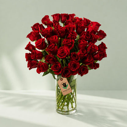 50 red roses arrangement in a transparent square glass vase.