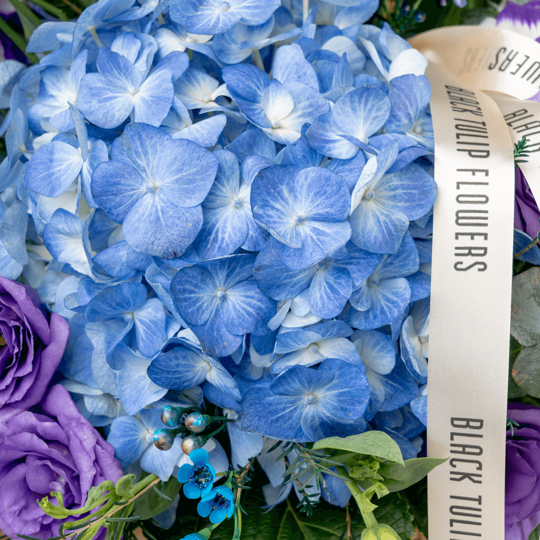 Blue and purple hydrangea, Eustoma, wax flower and agapanthus arrangement in a round basket