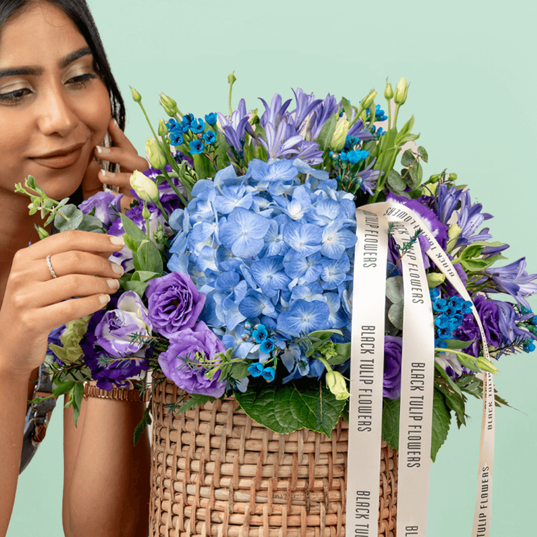 Blue and purple hydrangea, Eustoma, wax flower and agapanthus arrangement in a round basket