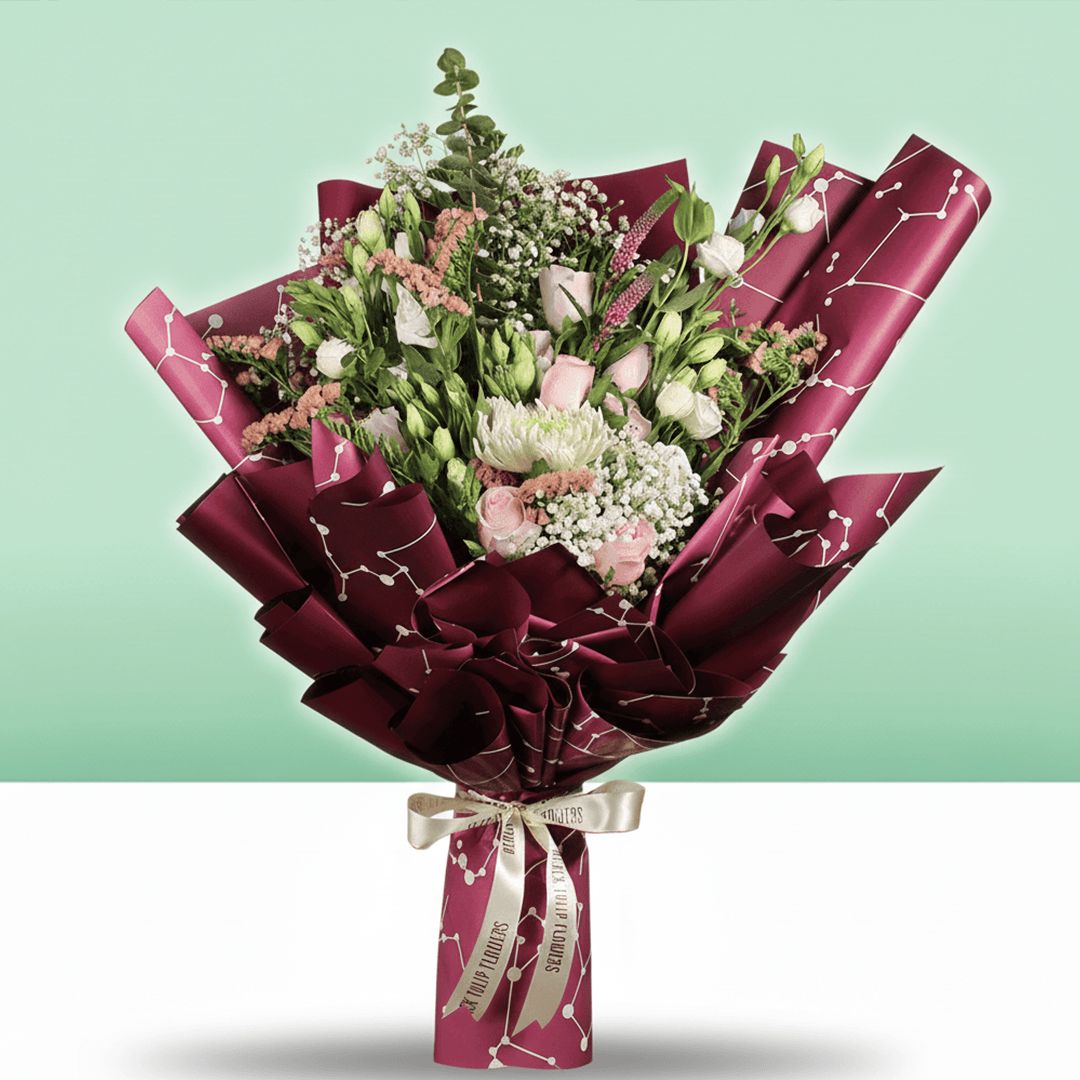 A bouquet of disbuds, Eustoma, roses and statice with fresh greenery wrapped in burgundy Korean-style flower sheets
