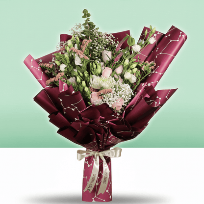 A bouquet of disbuds, Eustoma, roses and statice with fresh greenery wrapped in burgundy Korean-style flower sheets

