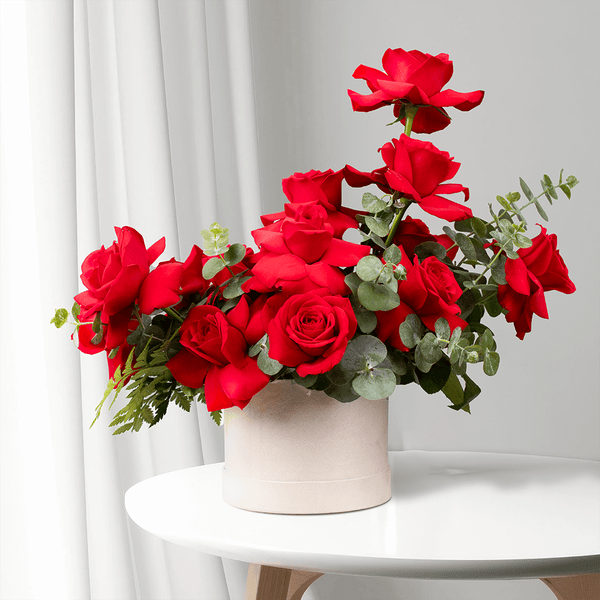 Red Roses with Eucalyptus arranged in a white round flower box.