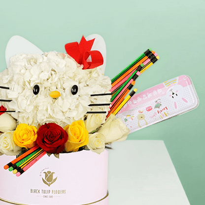 Round flower box featuring roses and hydrangeas in a Hello Kitty-inspired design, decorated with colourful stationery items.