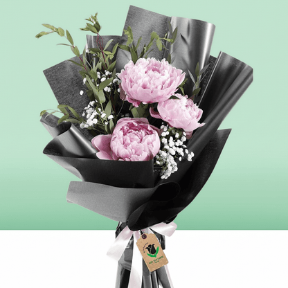 Pink peonies bouquet with baby’s breath and greenery in black non-woven wrapping