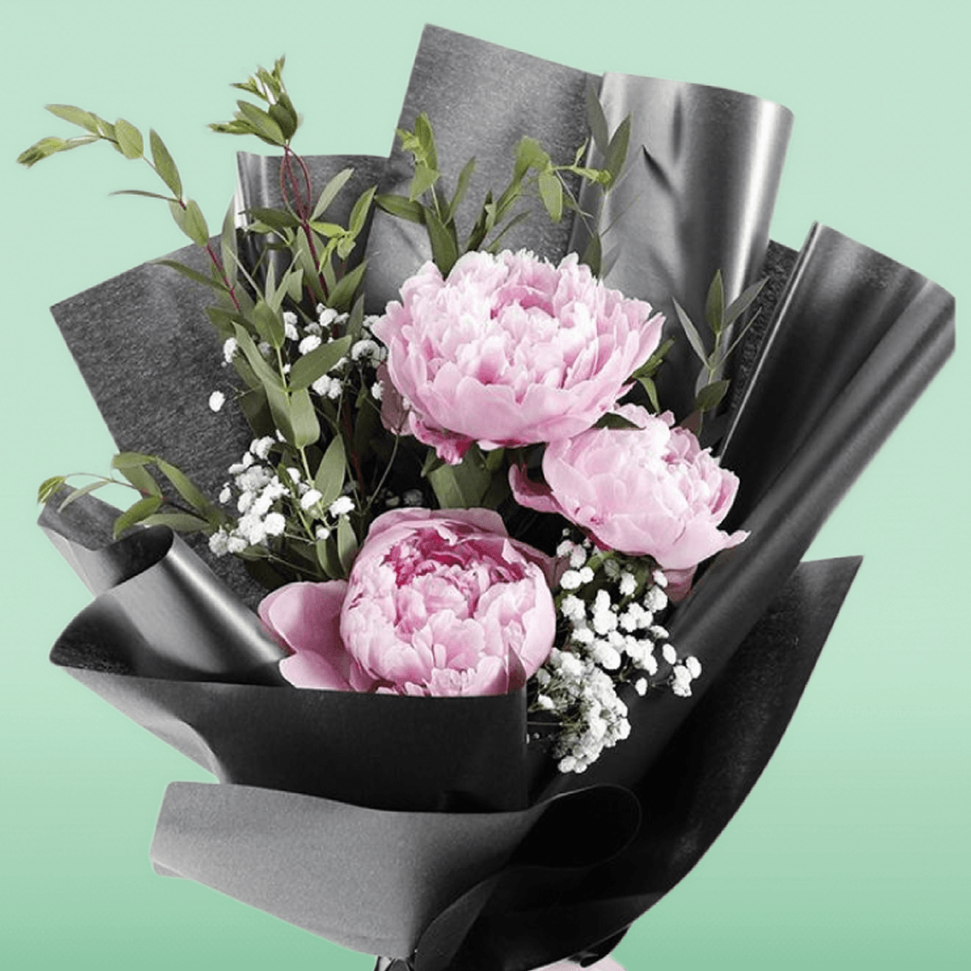 Pink peonies bouquet with baby’s breath and greenery in black non-woven wrapping