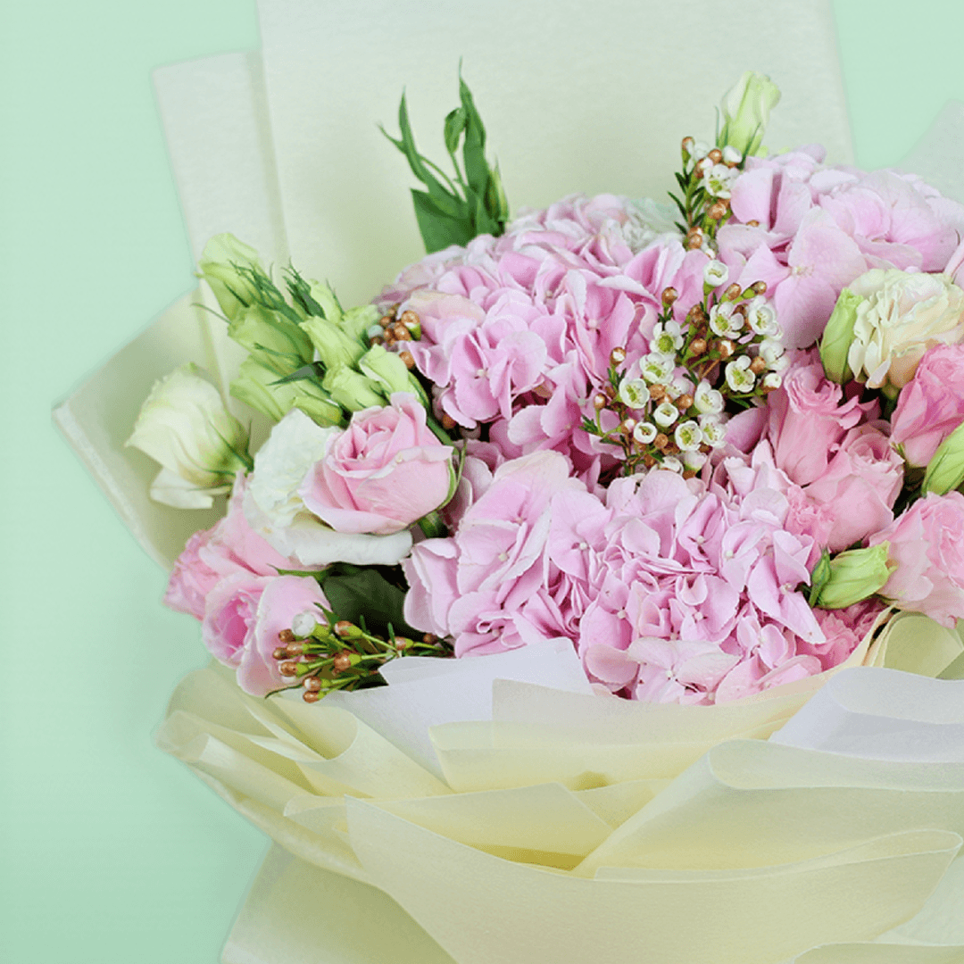 Bouquet of pink hydrangeas, roses, Eustoma and wax flowers arranged in layered ivory non-woven wrapping
