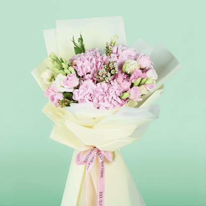 Bouquet of pink hydrangeas, roses, Eustoma and wax flowers arranged in layered ivory non-woven wrapping
