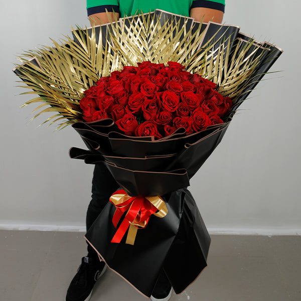 50 red roses with gold-toned palm leaves in black Korean-style wrapping