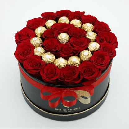 Red roses arranged with 16 Ferrero Rocher chocolates in a black round gift box