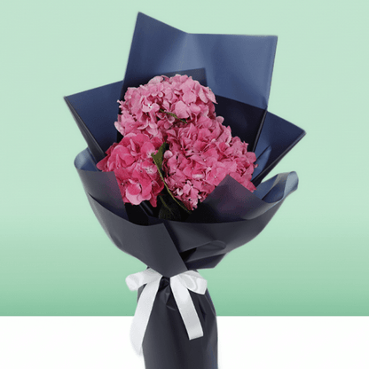 Dark pink hydrangea bouquet wrapped in navy non-woven paper with a white ribbon
