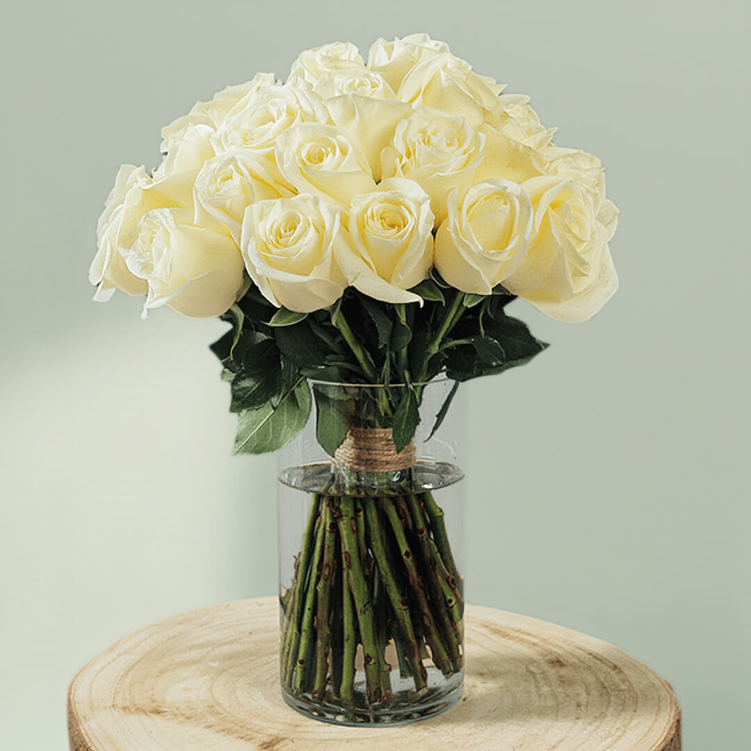 30 fresh white roses with vibrant green foliage are elegantly arranged in a transparent cylinder glass vase.