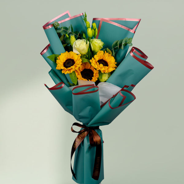 Sunflower bouquet with white roses, Eustoma and greenery wrapped in stylish teal floral paper.