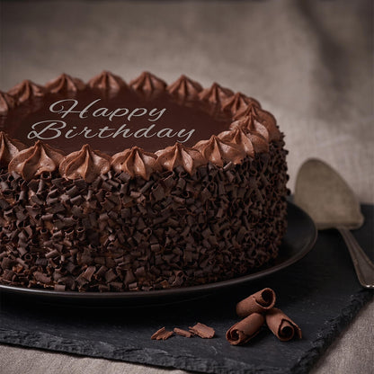 Chocolate truffle cake featuring smooth chocolate ganache, piped frosting, fresh berries and decorative chocolate pieces.
