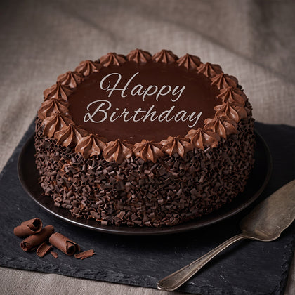 Chocolate truffle cake featuring smooth chocolate ganache, piped frosting, fresh berries and decorative chocolate pieces.