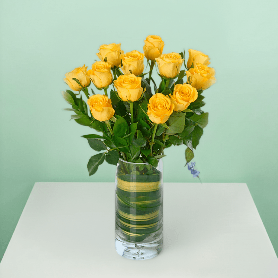 Vase arrangement with 20 yellow roses and fresh greenery in a transparent cylinder glass vase.