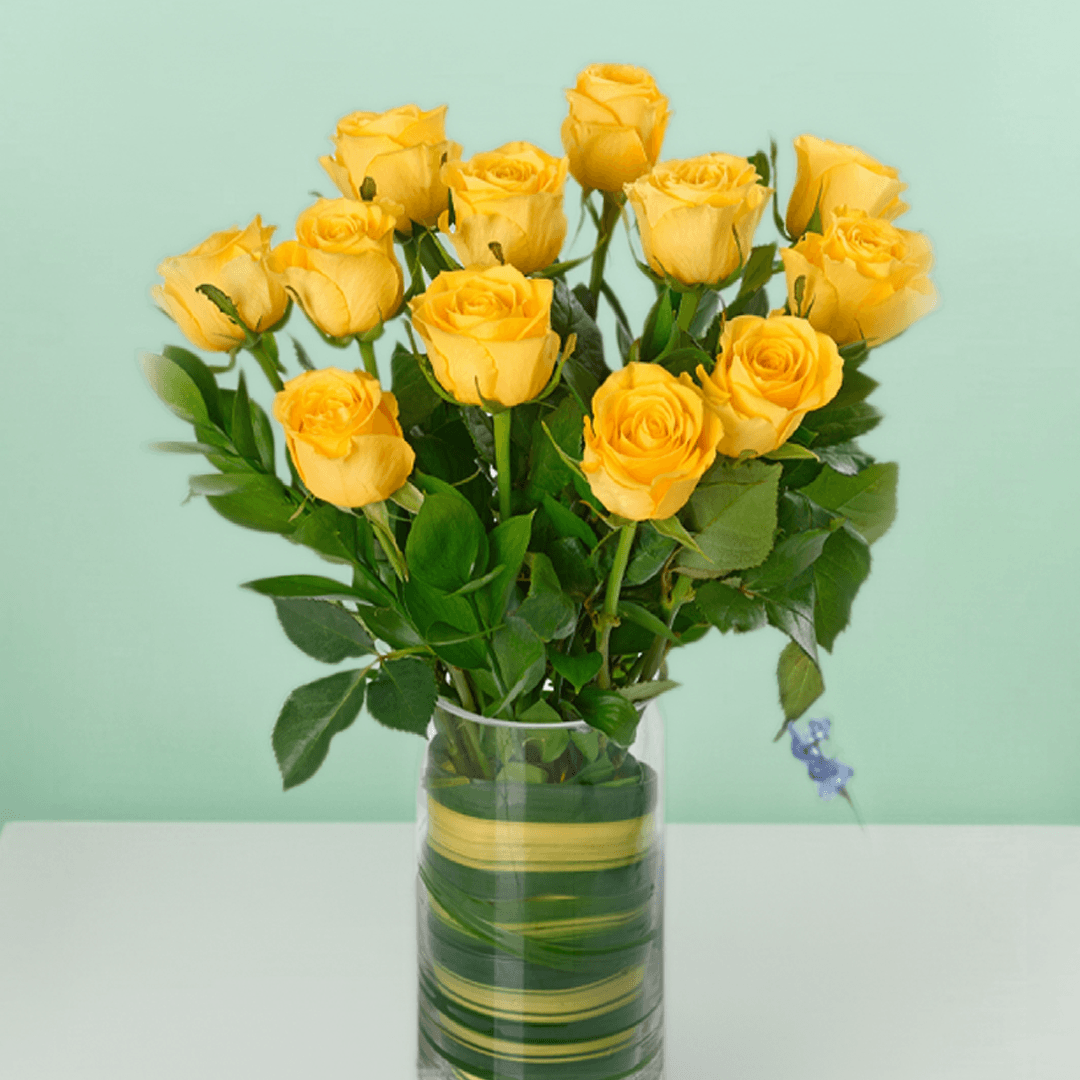 Vase arrangement with 20 yellow roses and fresh greenery in a transparent cylinder glass vase.