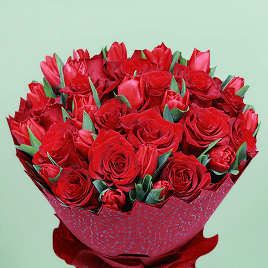 Bouquet of red roses and tulips arranged in layered red non-woven wrapping