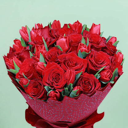 Bouquet of red roses and tulips arranged in layered red non-woven wrapping