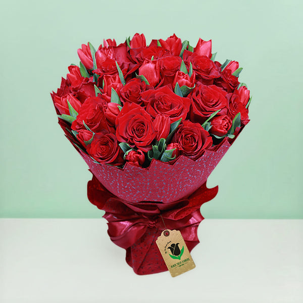 Bouquet of red roses and tulips arranged in layered red non-woven wrapping