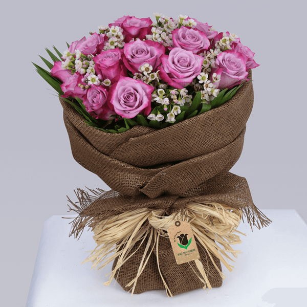 Purple roses with small wax flowers wrapped in brown jute and finished with natural raffia